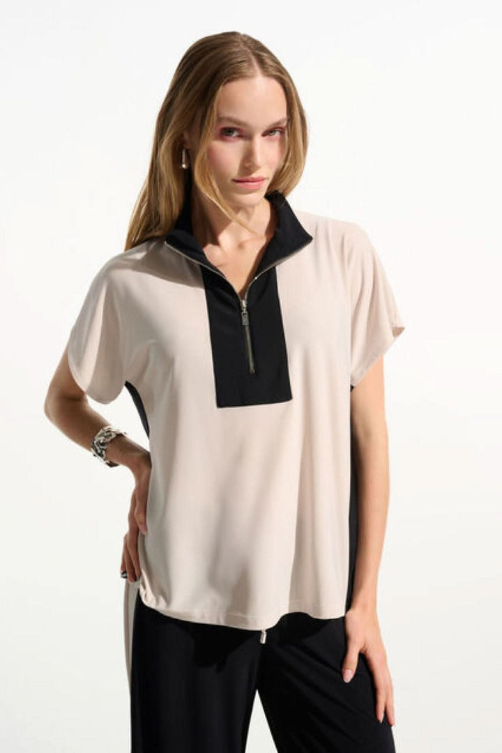 Haut à col zippé structuré avec manches courtes et coupe fluide, présenté par une femme formelle
