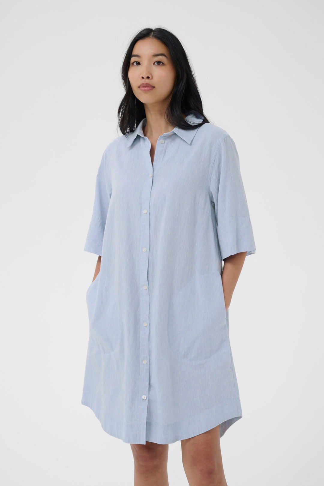 Femme portant une robe chemise Berrit fluide à manches courtes avec col chemise et poches.