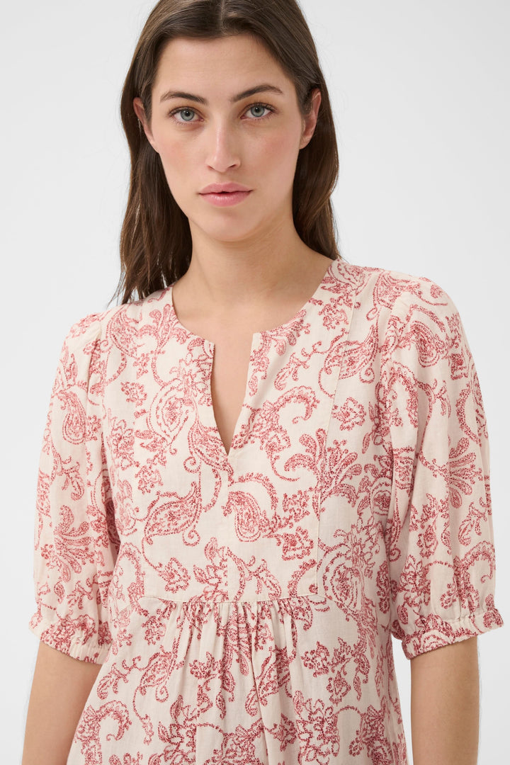 Robe fleurie Benete avec motif floral rouge, coupe fluide et encolure ouverte, idéale pour un look féminin et décontracté.