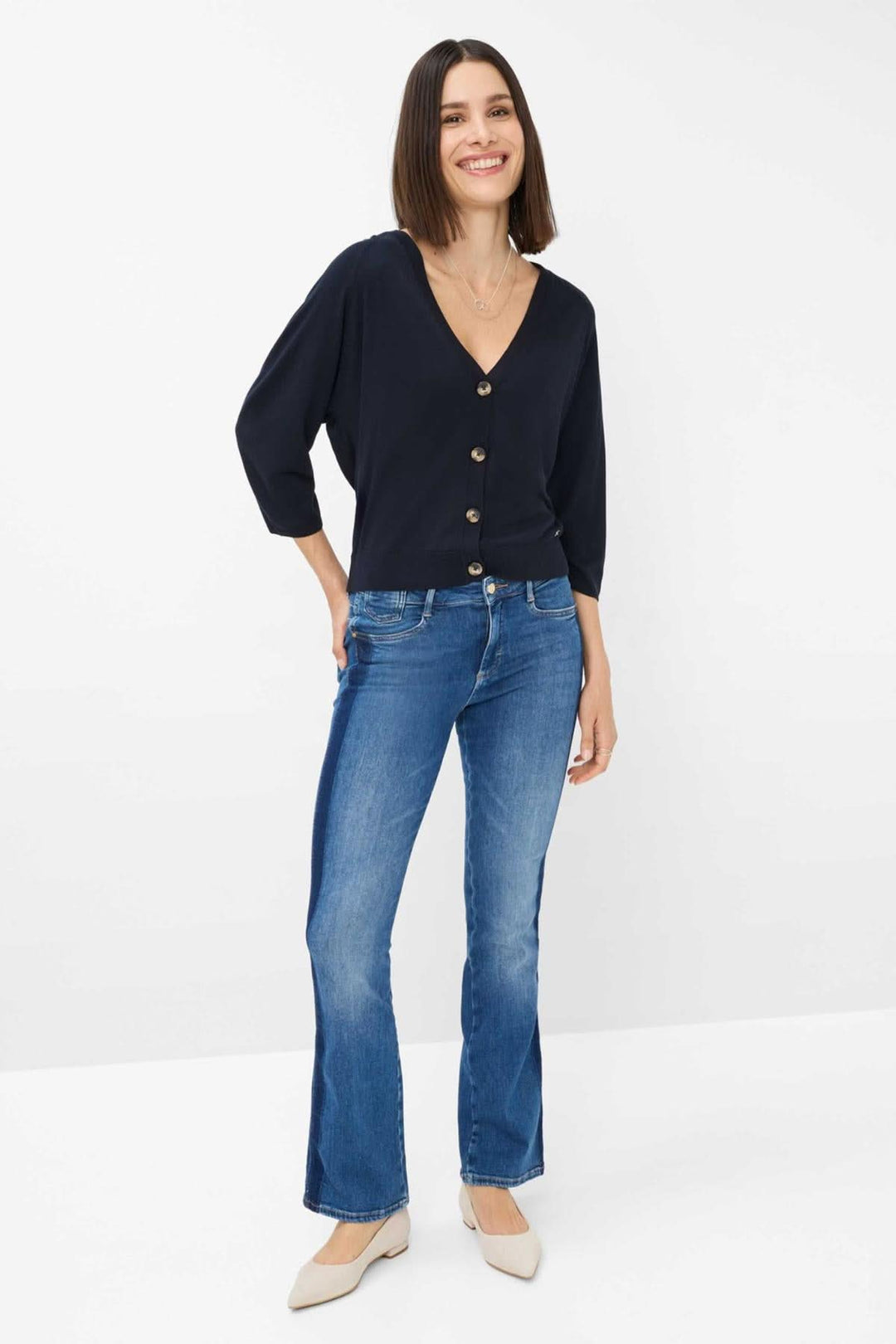 Cardigan Anique en maille fine, encolure V profonde, porté avec un jean ajusté, look élégant et décontracté.