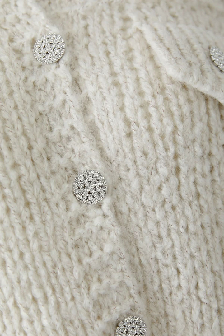 Détail de la veste en tricot épais à boutons bijoux avec maille texturée et boutons scintillants, chic pour l'automne et hiver.