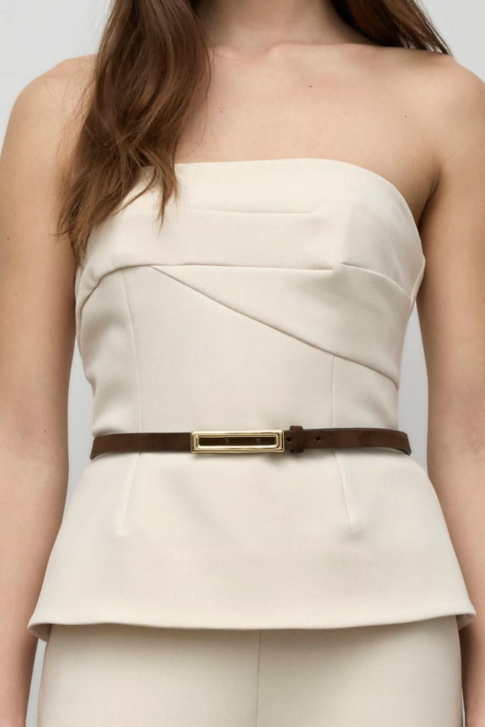 Haut bustier beige à bretelles amovibles, plissé délicat, porté avec une ceinture marron.