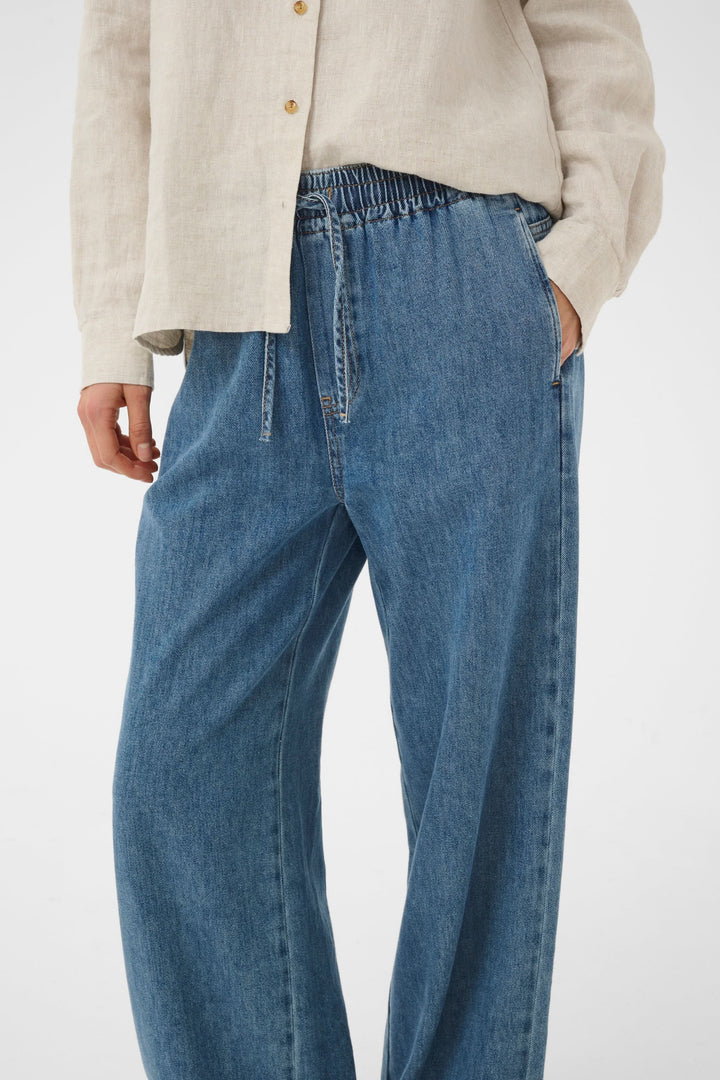 Jeans Sophina taille élastique jambe large avec poches latérales et tissu denim souple, offrant un confort optimal et allure décontractée.