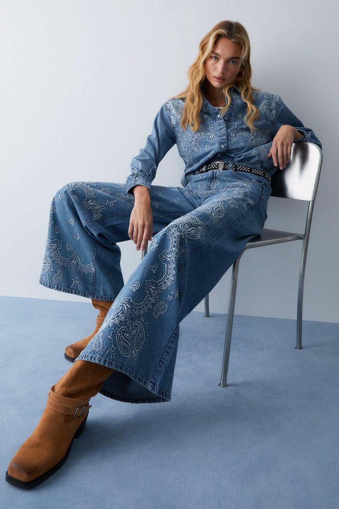 Jean à jambe large imprimé avec motif unique et coupe fluide en denim souple, allongeant la silhouette, porté avec des bottes marron.