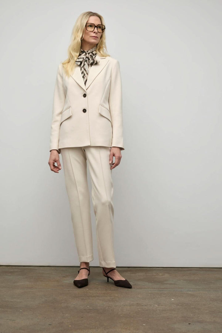 Femme portant un veston semi-ajusté beige avec pantalon assorti et foulard noir, style élégant et professionnel.