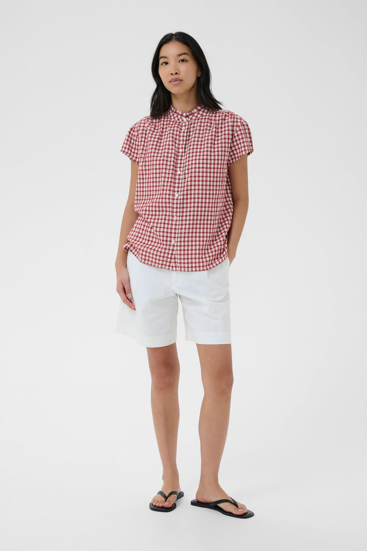 Blouse Bjanka à carreaux col montant boutonné portée par une femme