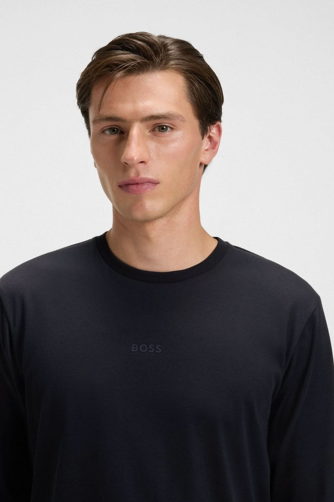 Homme portant un pull noir avec logo BOSS, partie de l'ensemble pyjama en coton avec logo BOSS.