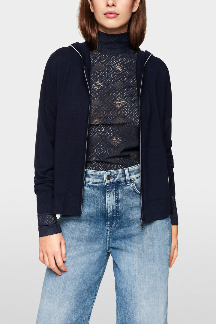 Cardigan tricoté à capuchon zippé, style décontracté avec détails contrastants, porté avec un haut en dentelle.