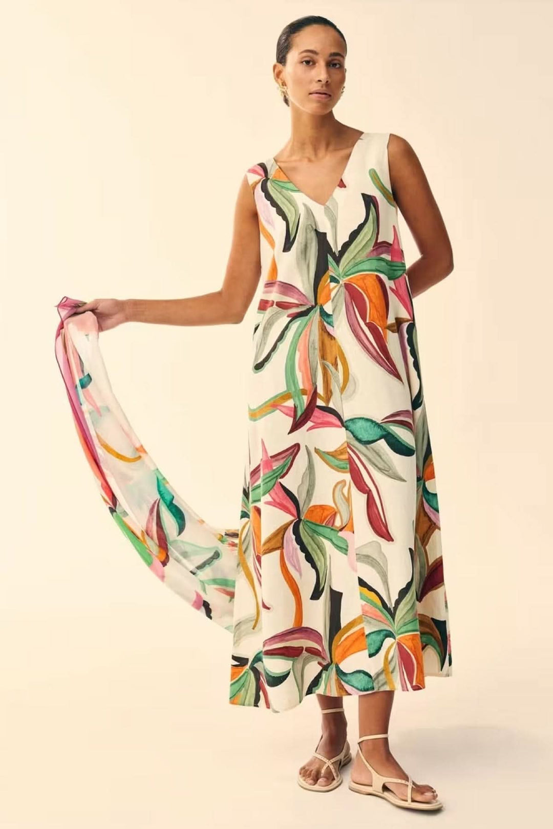 Femme portant une robe longue fluide imprimée à col v avec motif artistique coloré.