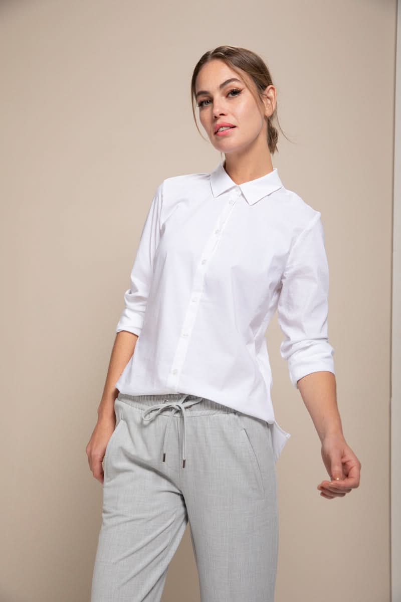Femme portant une chemise classique blanche à manches 3/4 avec un style moderne et épuré, idéale pour le bureau ou des tenues décontractées.