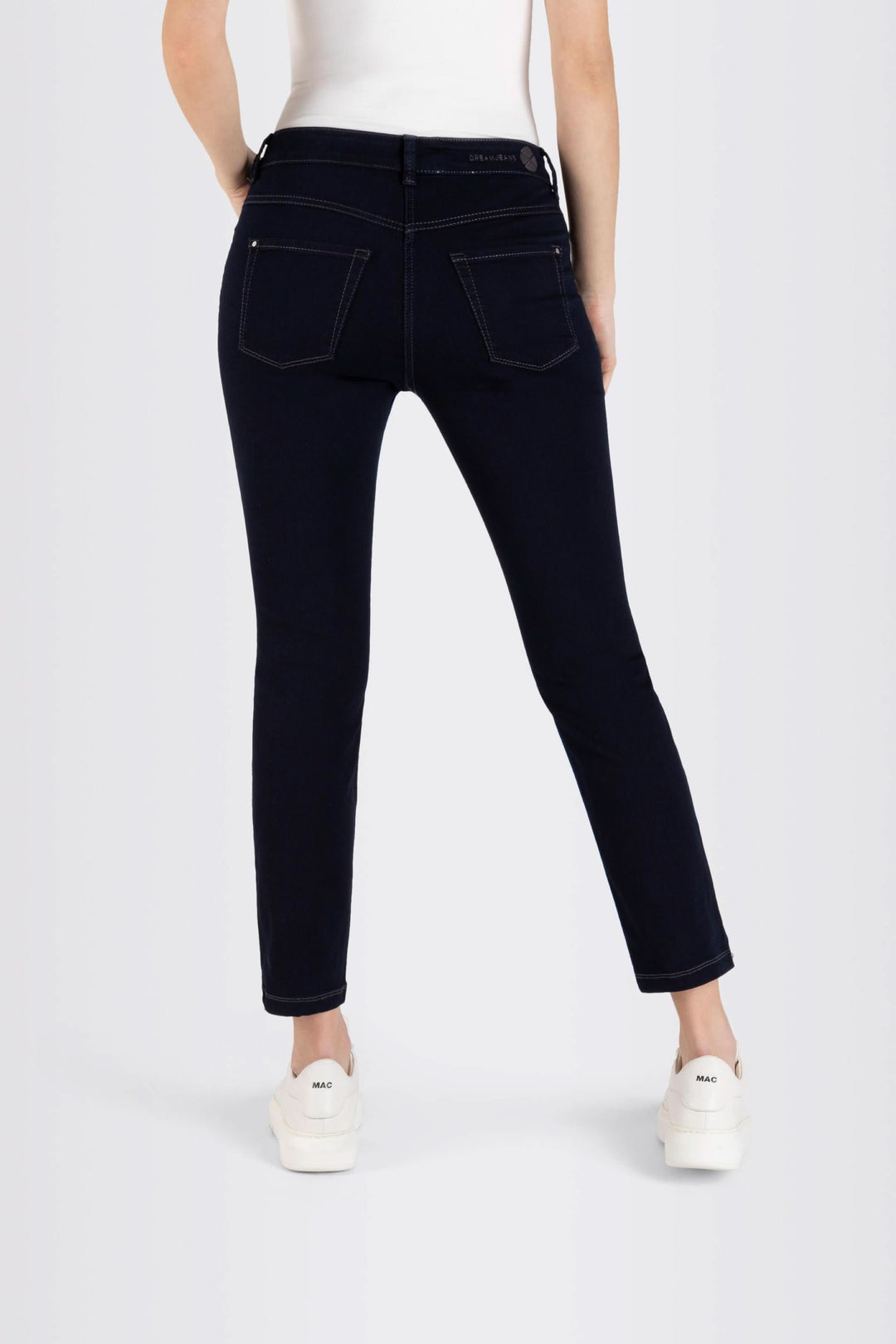 Femme portant des jeans coupe ajustée 7/8 avec surpiqûres contrastantes et sneakers blanches