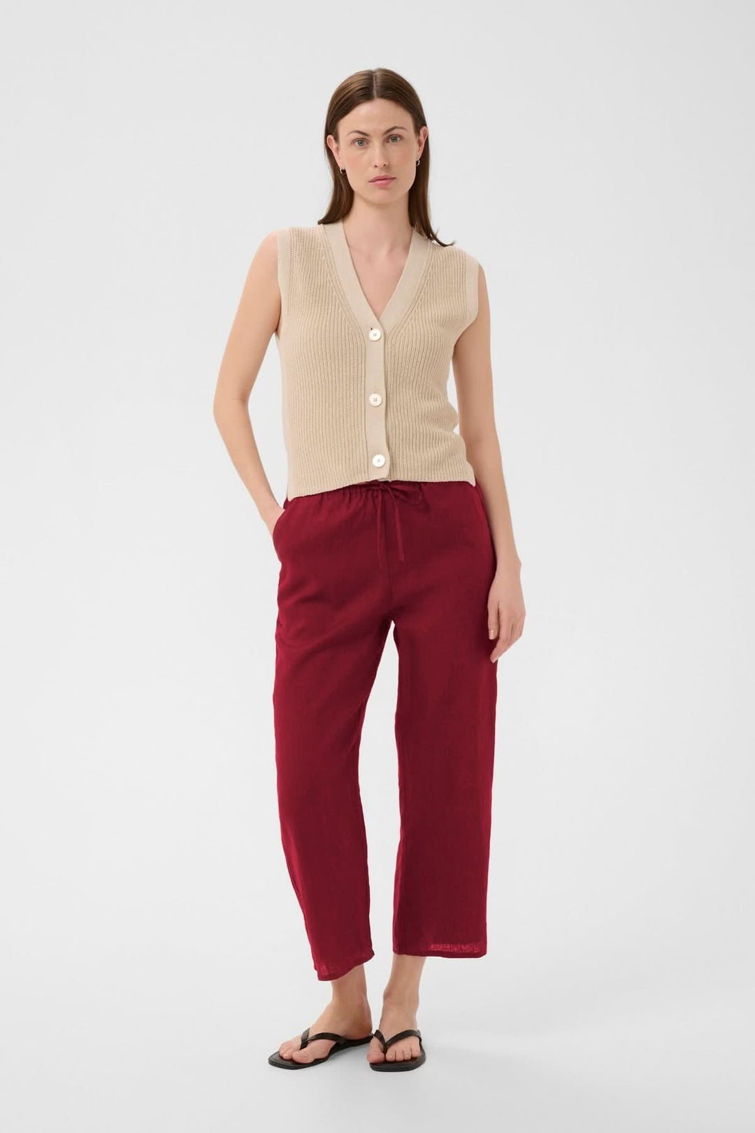Femme portant le Pantalon de lin Berita rouge avec taille élastique et coupe droite, parfait pour un style décontracté et estival.