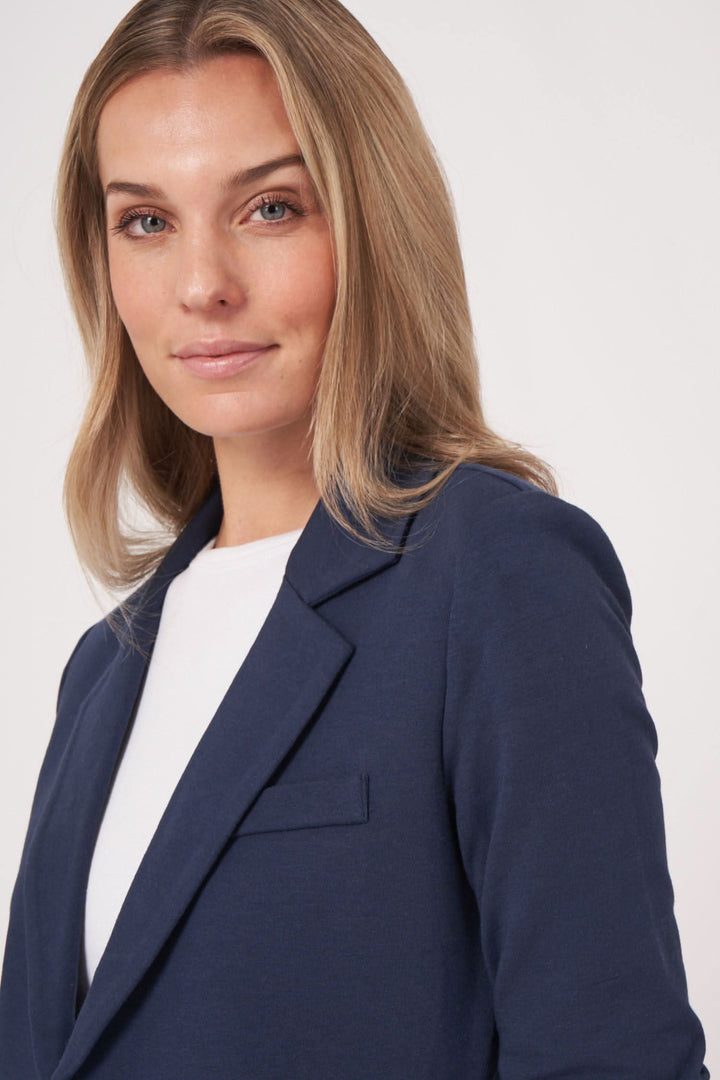 Femme souriante portant un veston en jersey stretch, alliant élégance et confort.