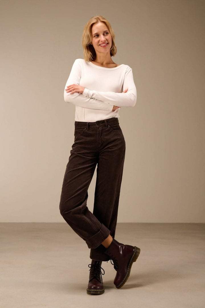 Femme portant un pantalon en velours côtelé coupe droite, stylé et confortable, avec un haut blanc décontracté et des chaussures marron.