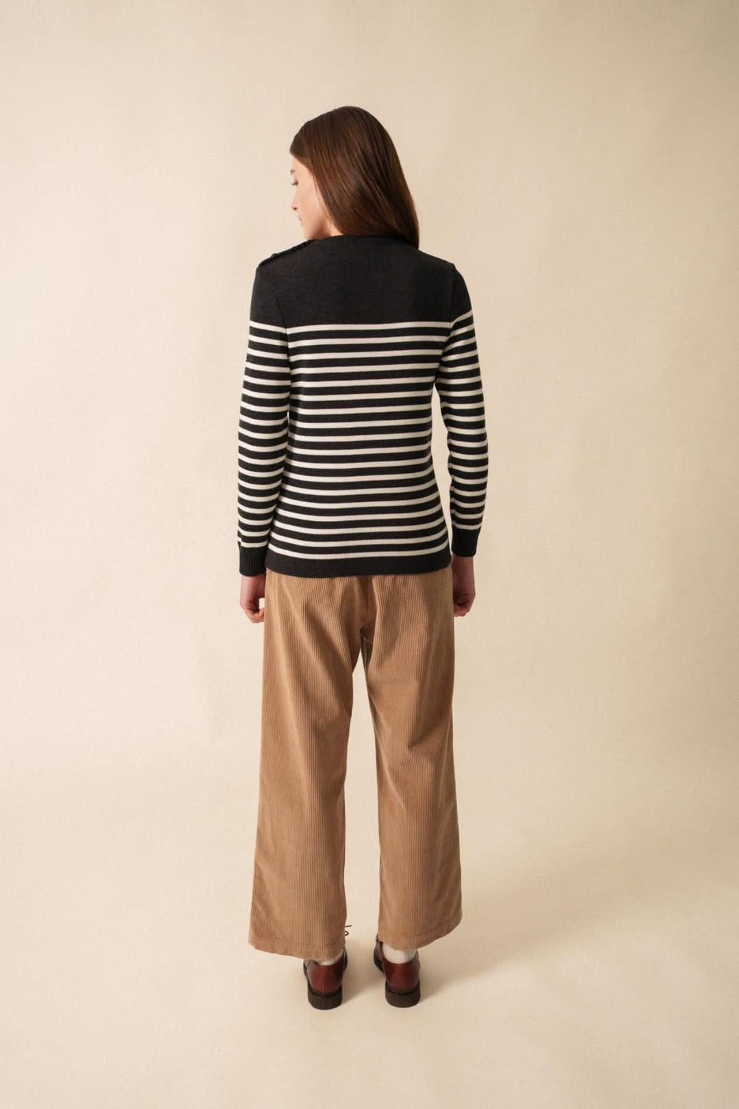 Chandail Rochefort en laine mérinos, rayé noir et blanc, porté avec un pantalon beige, vue de dos.