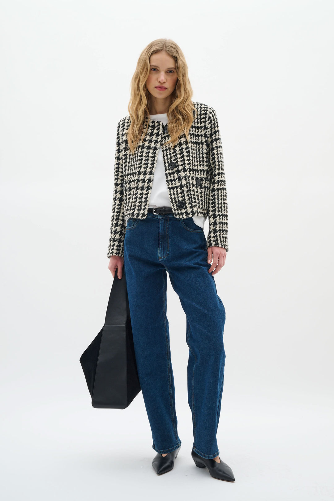 Modèle féminin portant une veste courte à motif pied-de-poule avec un t-shirt et jean, style moderne et élégant.