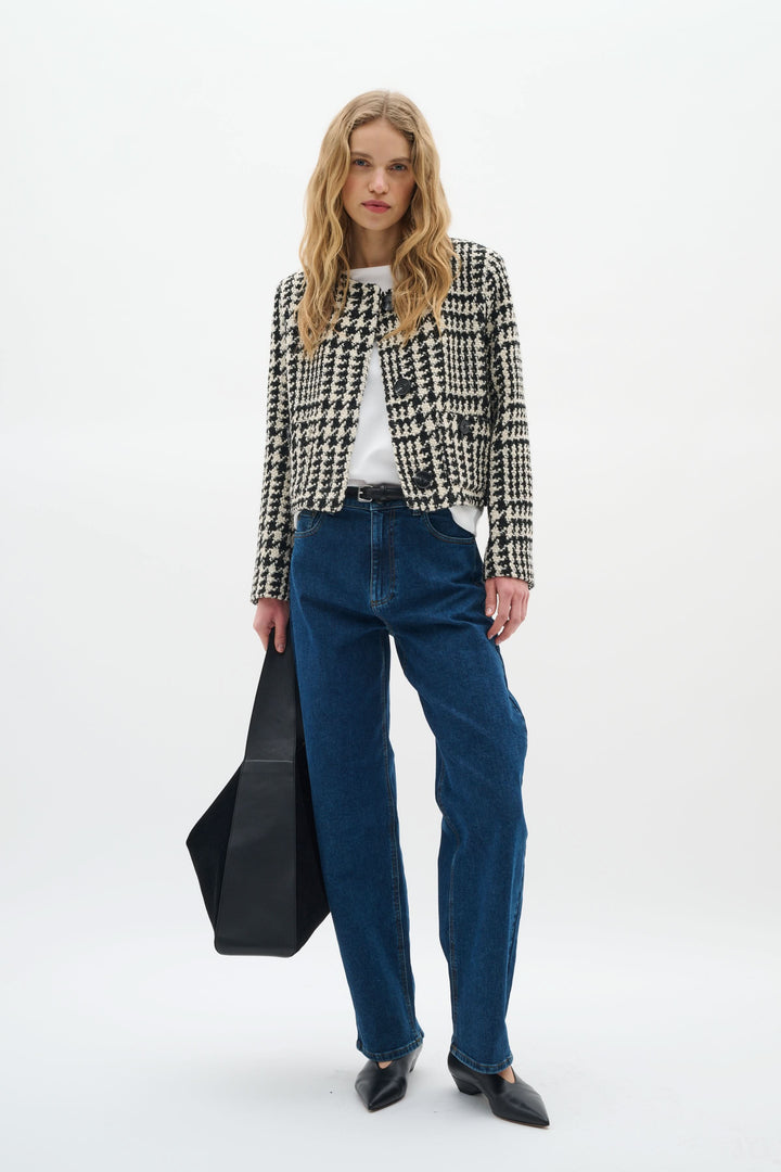 Modèle féminin portant une veste courte à motif pied-de-poule avec un t-shirt et jean, style moderne et élégant.