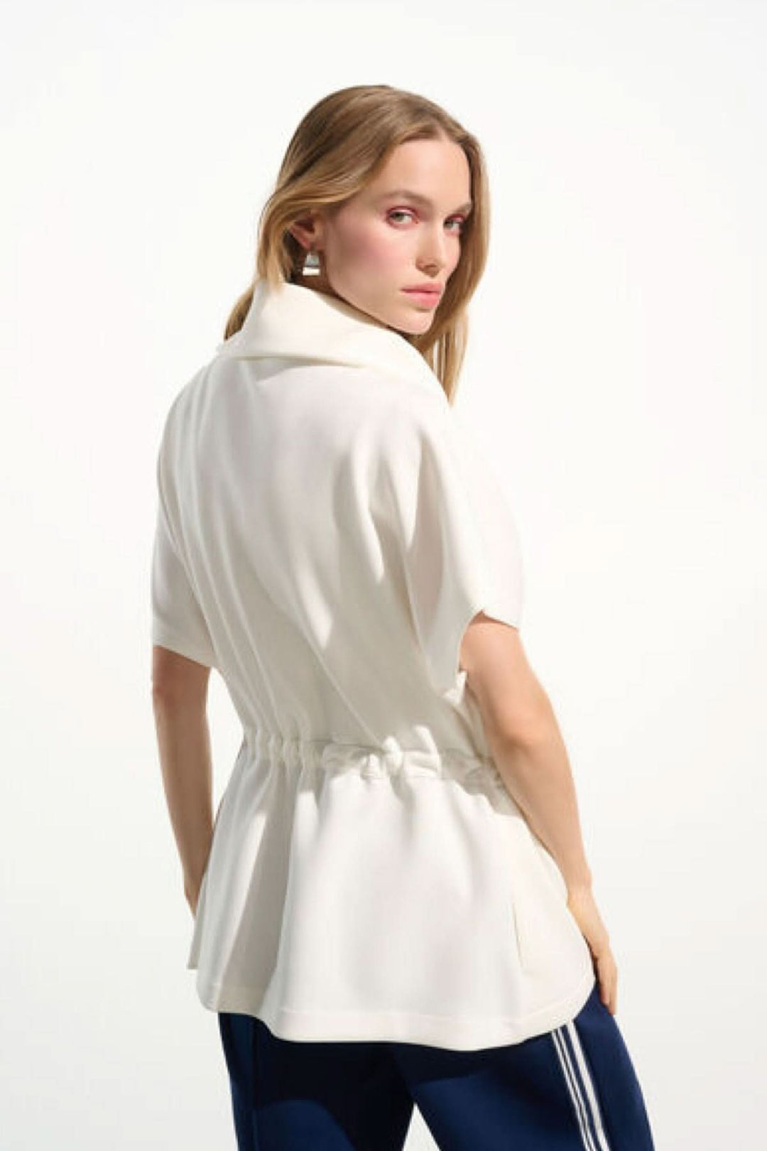 Veste zippée à col large en blanc, avec manches courtes et taille ajustable, vue de dos, style moderne et confortable idéal pour le quotidien.