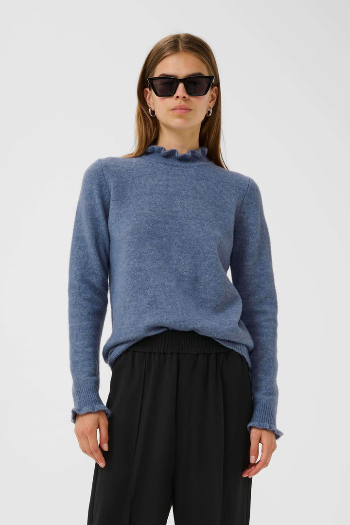 Tricot Guni col montant froncé, maille douce, confortable, porté avec pantalon fluide pour look chic.