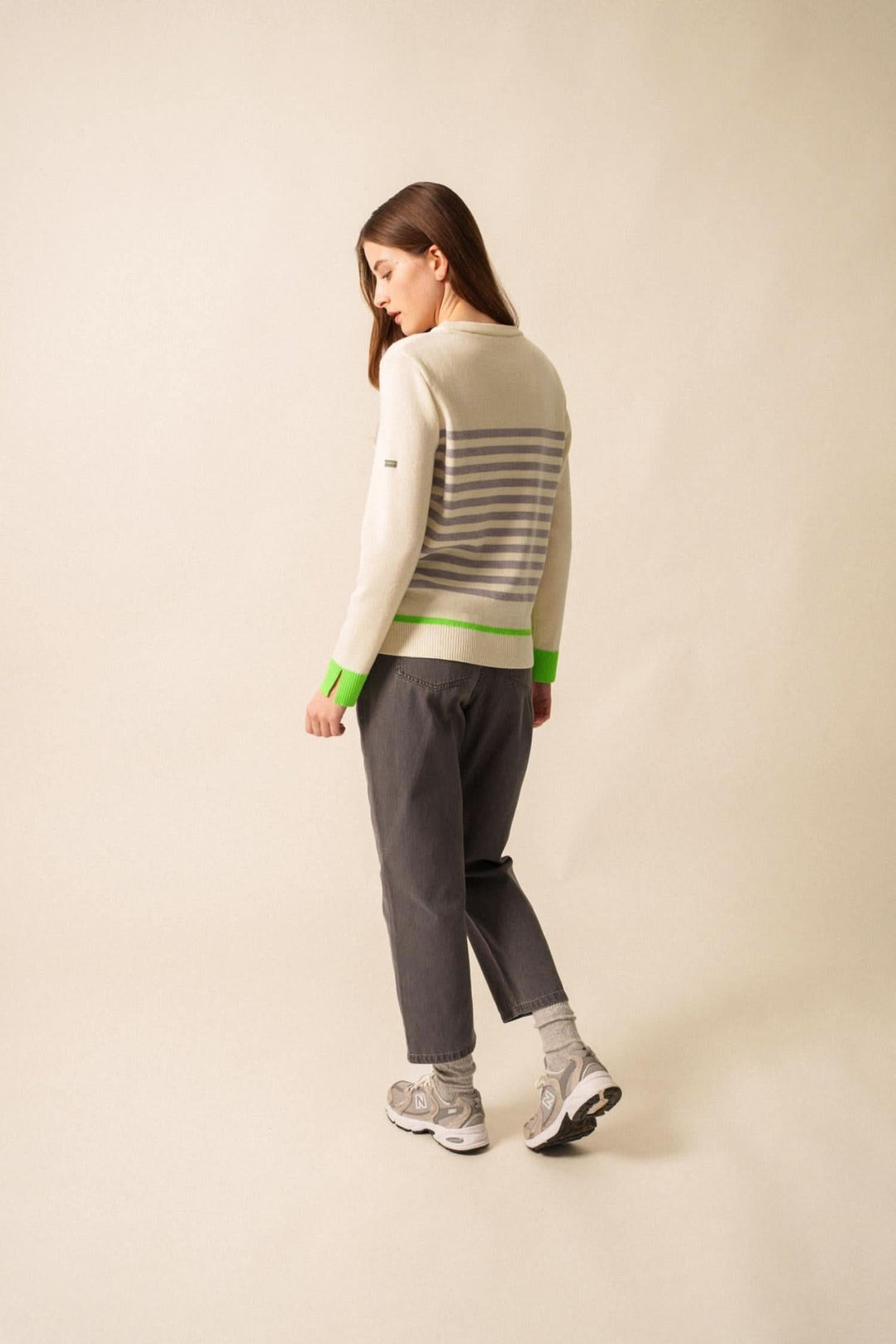 Chandail Evian rayé avec finitions fluo, porté avec un pantalon gris, style moderne et décontracté.