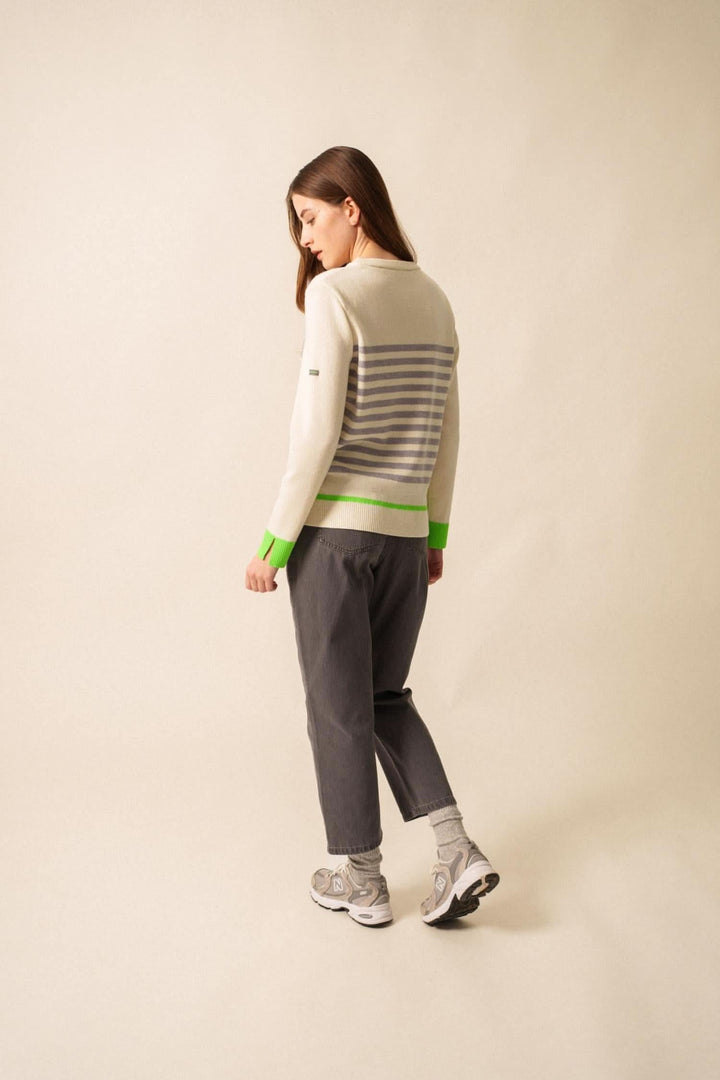 Chandail Evian rayé avec finitions fluo, porté avec un pantalon gris, style moderne et décontracté.