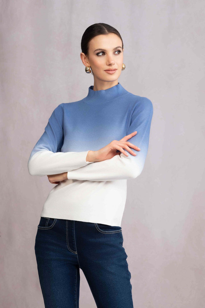 Tricot col montant dégradé bleu et blanc avec manches longues, porté avec un jean, look moderne et élégant.