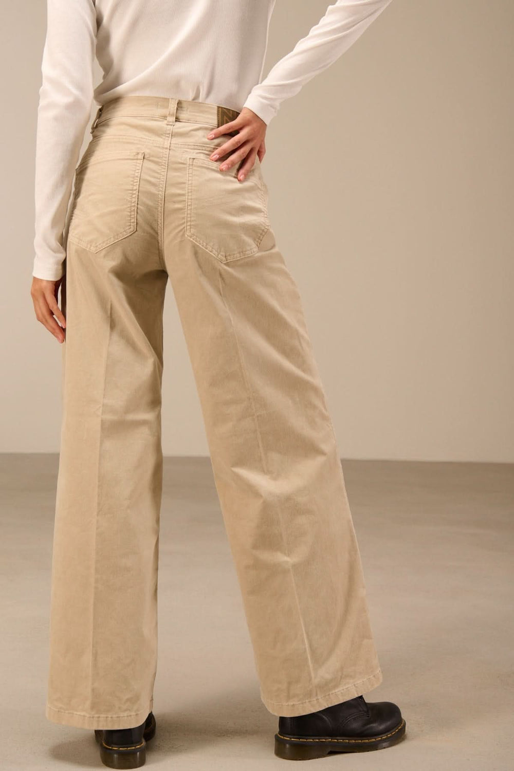 Pantalon large taille haute beige avec design à la mode, matière souple et deux poches arrière, idéal pour un look moderne.