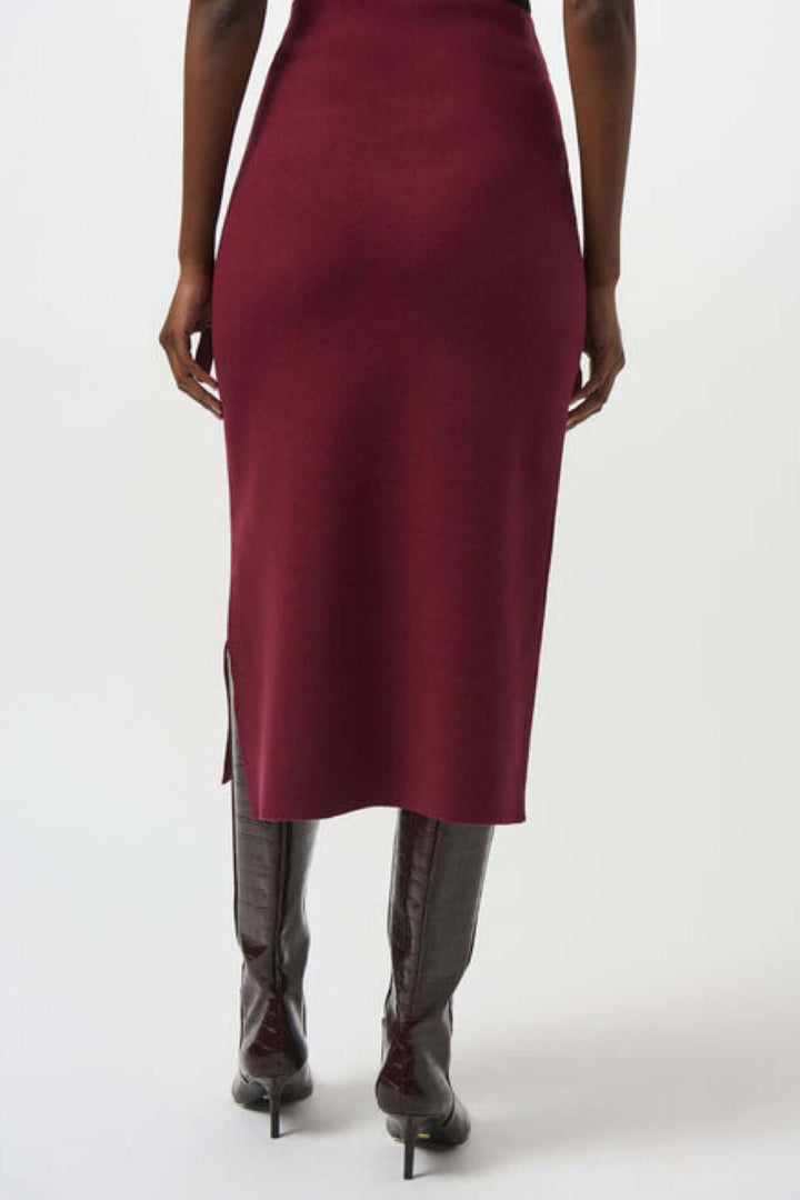 Jupe crayon en tricot bordeaux, longueur midi, coupe ajustée, portée avec des bottes.