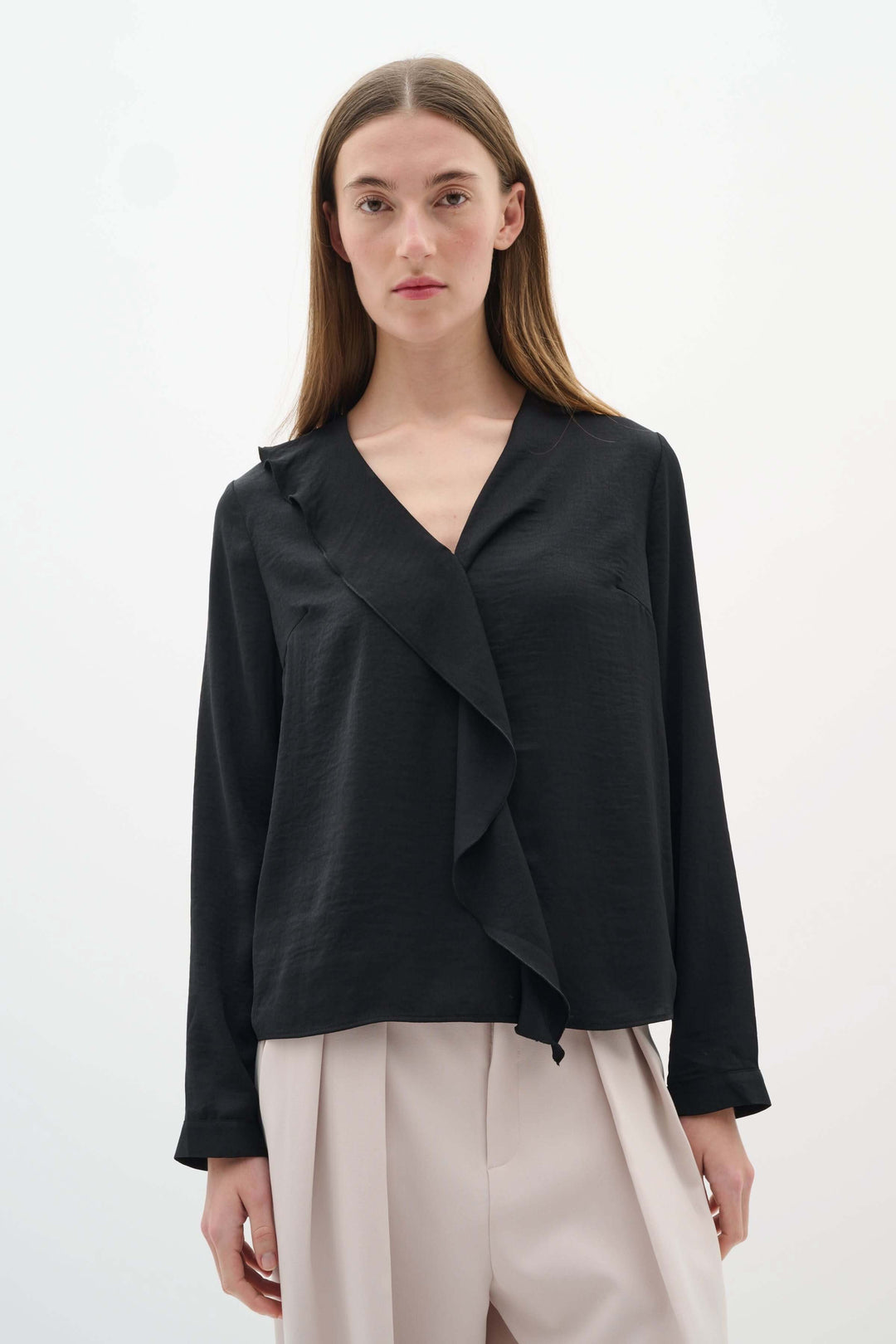 Blouse Auda noire fluide avec col en V et volant, parfaite pour un look chic et sophistiqué.