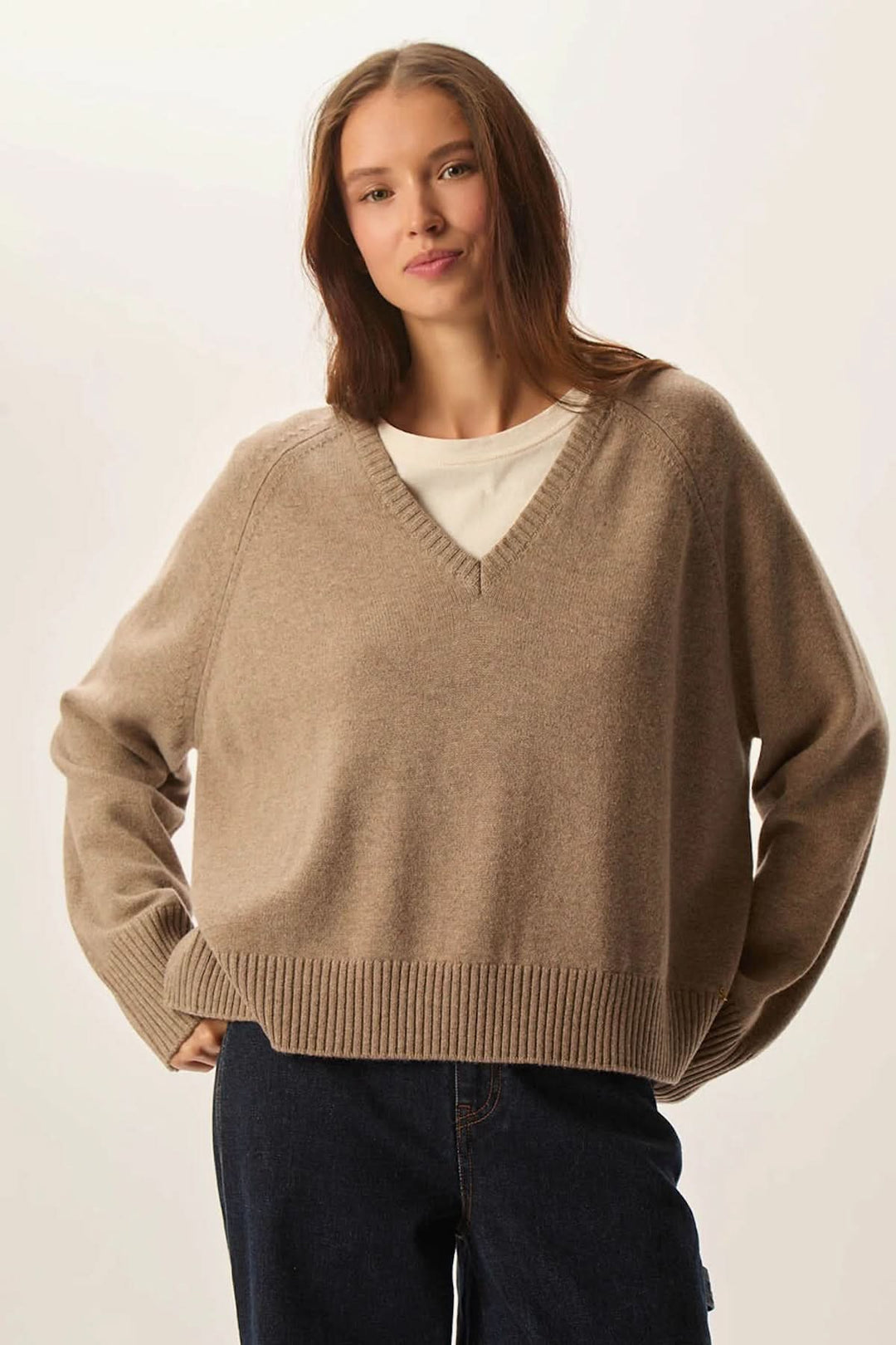 Femme portant un chandail à col en V en laine mérinos ultrafine, couleur taupe, maille douce et coupe ample pour confort et style.