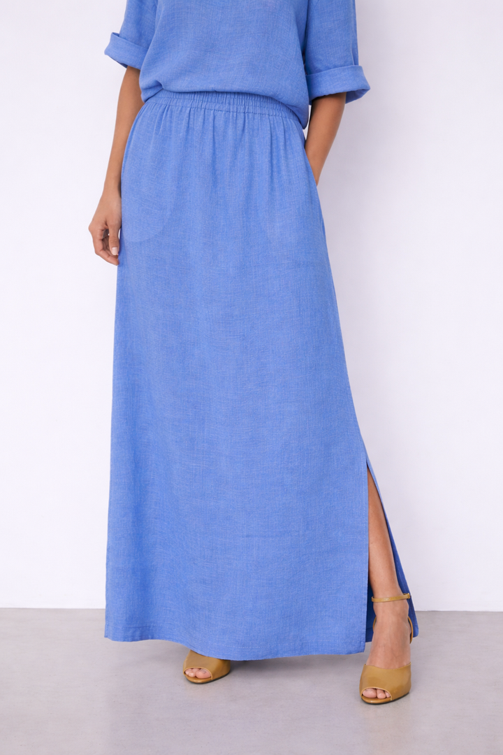 Jupe Vivienne longue fluide taille élastique en bleu avec fente, offrant élégance et confort parfaits pour un look estival raffiné.