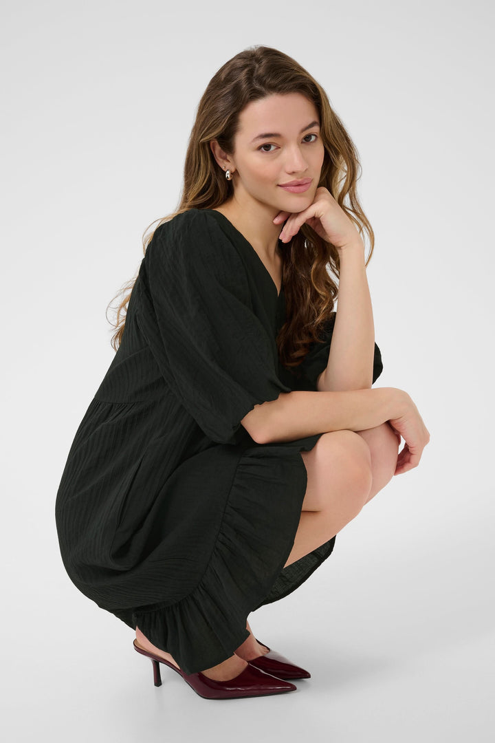 Robe courte Lianna en mousseline noire, encolure en V et manches bouffantes, style romantique et décontracté.