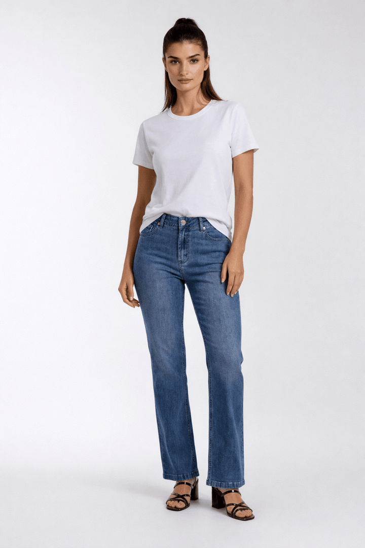 Femme portant un jeans coupe droite avec taille mi-haute, fermeture bouton et glissière, idéal pour une garde-robe polyvalente.