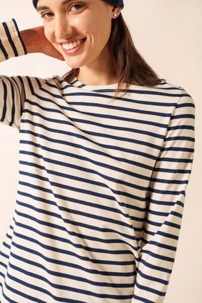 Femme souriante portant un chandail à rayures marines, en coton doux et à encolure bateau.