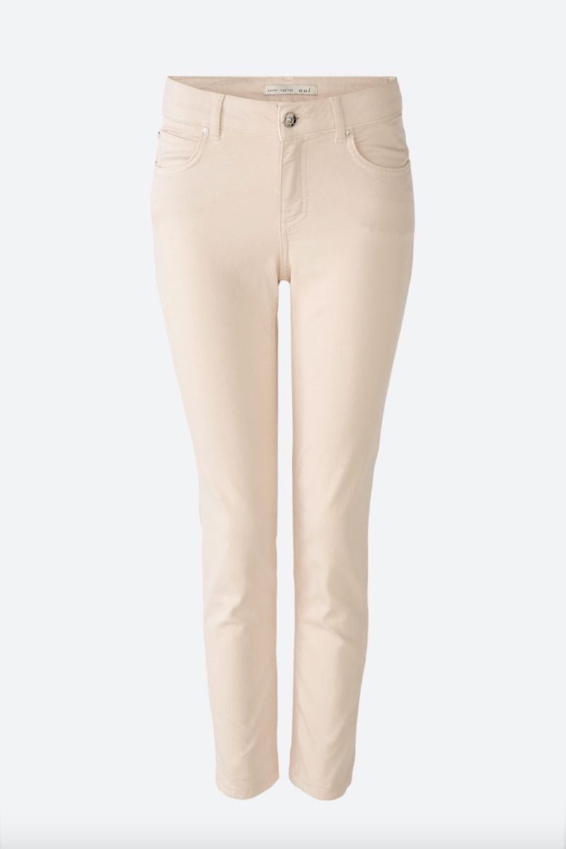 Pantalon ajusté beige avec fermeture éclair et cinq poches, longueur légèrement raccourcie.