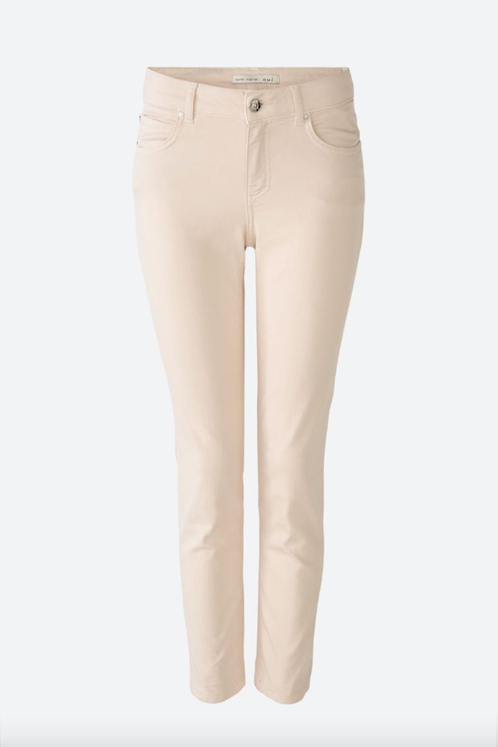 Pantalon ajusté beige avec fermeture éclair et cinq poches, longueur légèrement raccourcie.