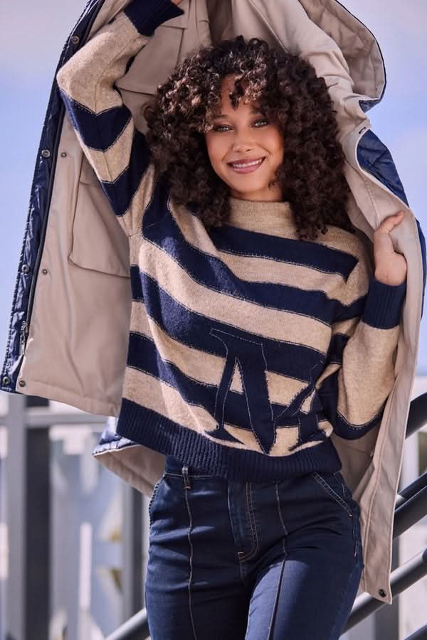 Modèle portant un chandail à rayures avec col montant, style décontracté chic, détails jacquard, idéal avec jean ou pantalon tailleur.