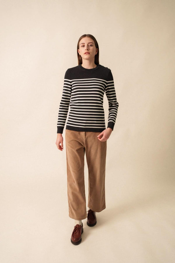 Femme portant un chandail en laine mérinos à rayures marines et un pantalon en velours, style élégant et confortable.
