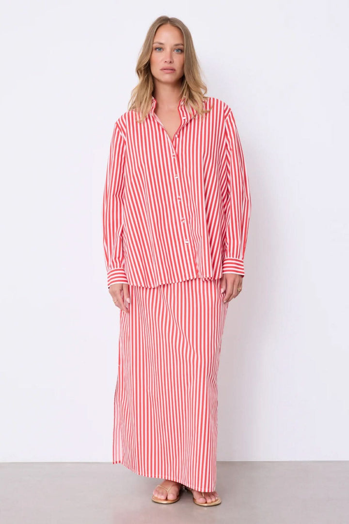 Femme portant une chemise rayée Althea coupe fluide classique rouge avec rayures verticales.