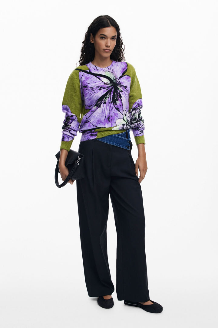 Chandail floral à col rond, imprimé oversize aux teintes vibrantes, porté avec pantalon noir.