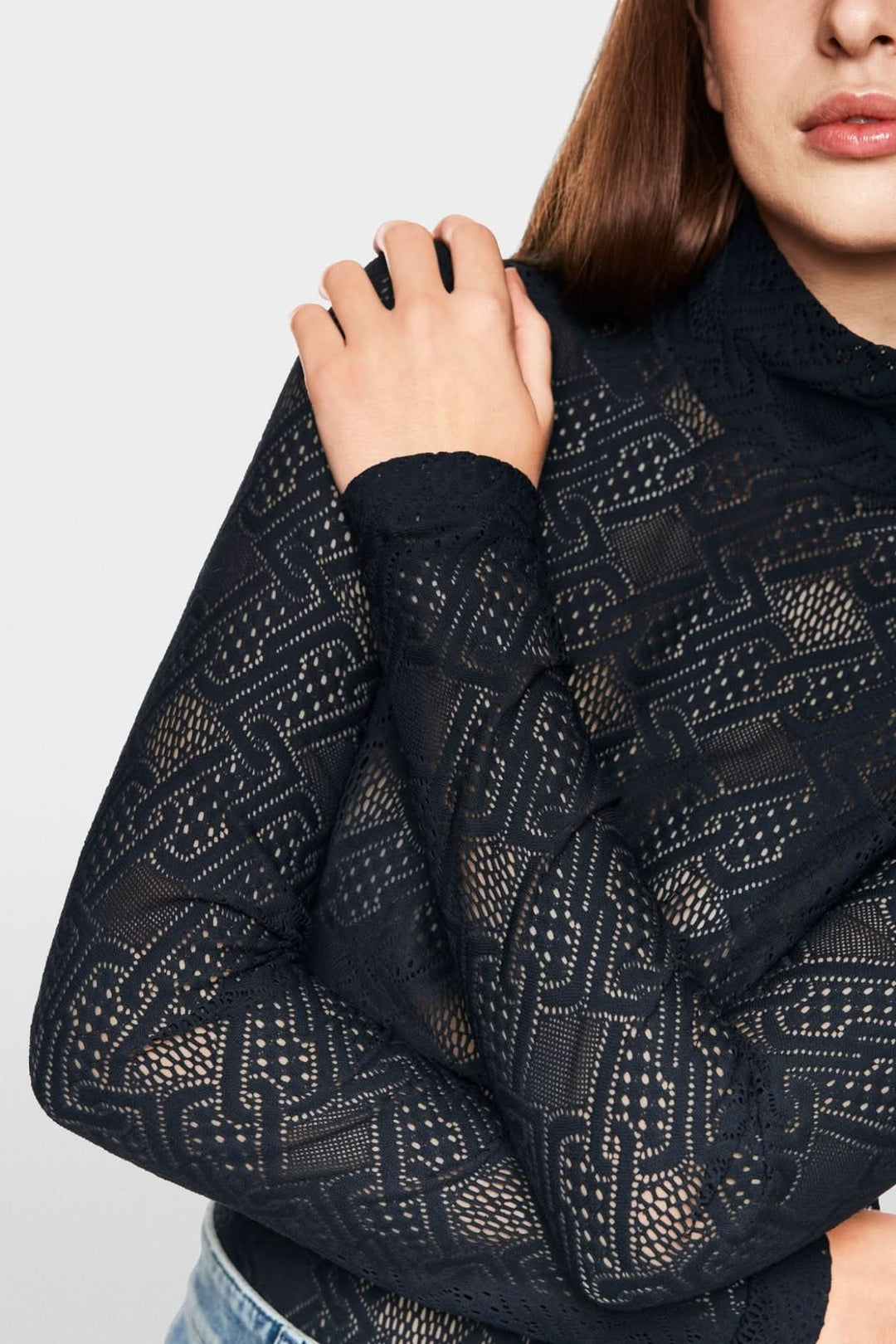 Haut en dentelle noir à manches longues, coupe ajustée et col montant pour un look moderne et féminin.