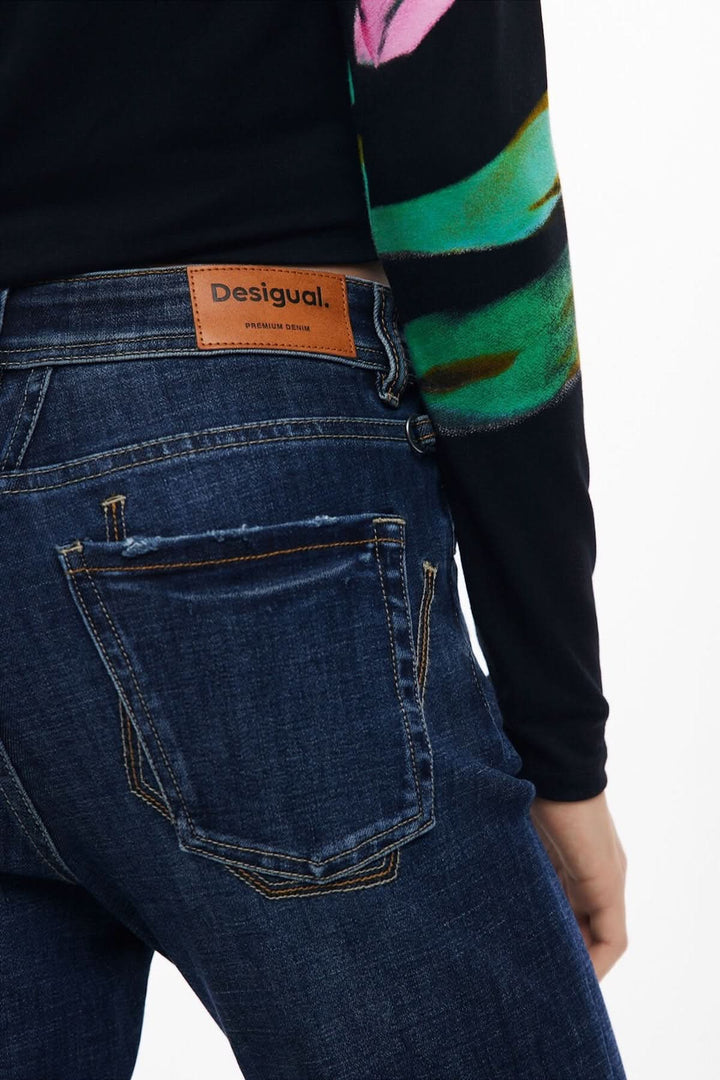 Vue arrière d'un jean évasé Desigual avec détails usés et étiquette en cuir.