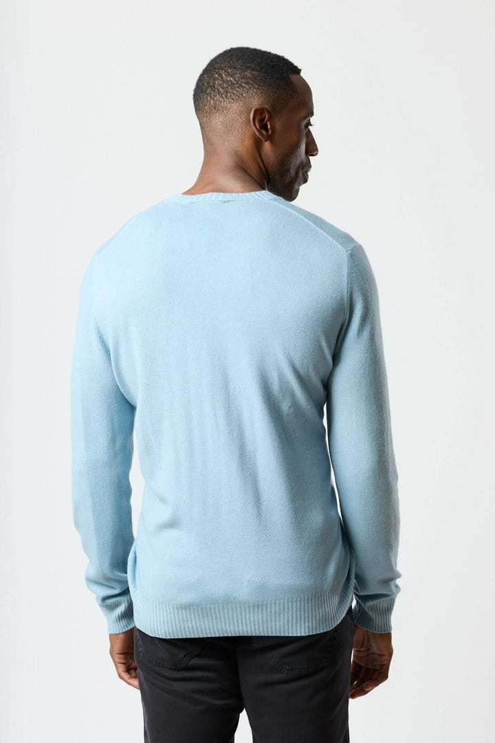 Homme portant un chandail col rond en maille douce bleu, vue de dos, style polyvalent et moderne.