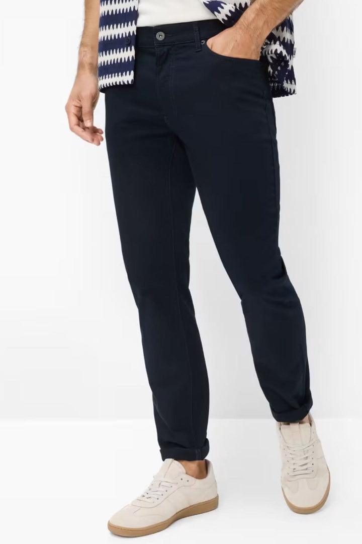 Homme portant un pantalon ajusté extensible noir avec chemise et baskets blanches.