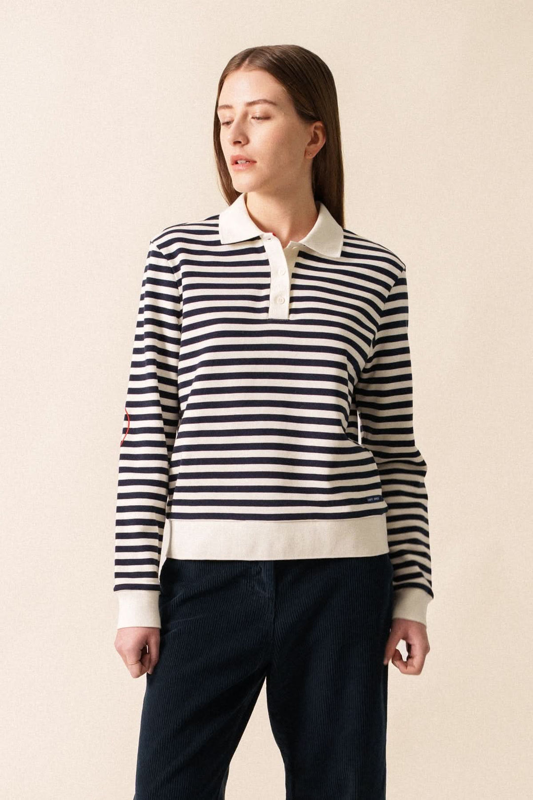 Femme portant un polo NINA rayé classique avec col et manches en bord-côte, style décontracté.