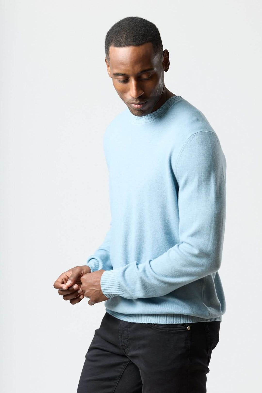 Homme portant un chandail col rond en maille douce bleu, style moderne et propre.