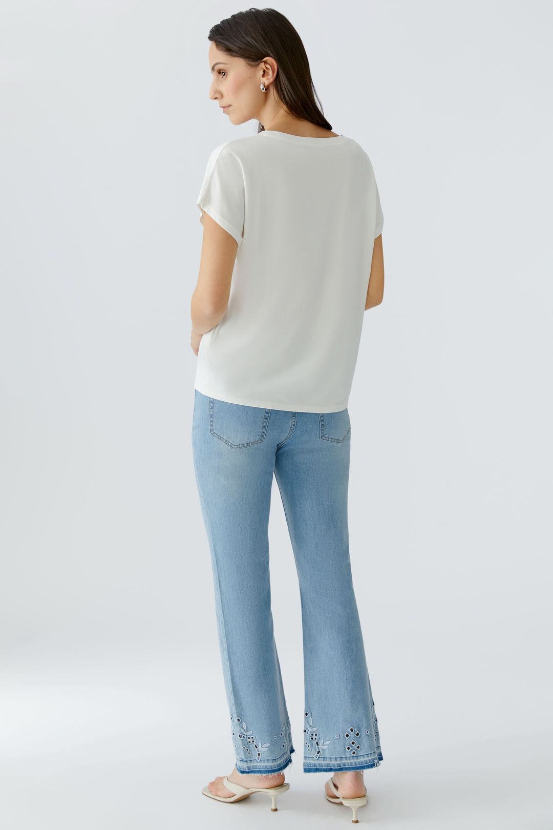 Vue arrière d'une femme portant un t-shirt imprimé à manches courtes et un jean bleu clair.