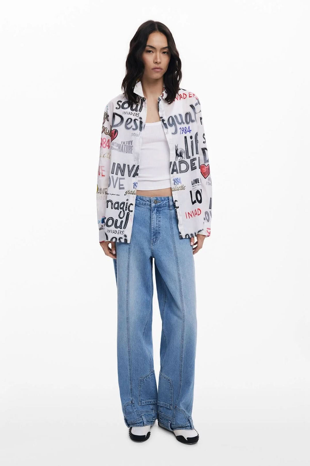 Chemisier à manches longues avec imprimé graffiti multicolore porté par un modèle, associé à un pantalon en denim.