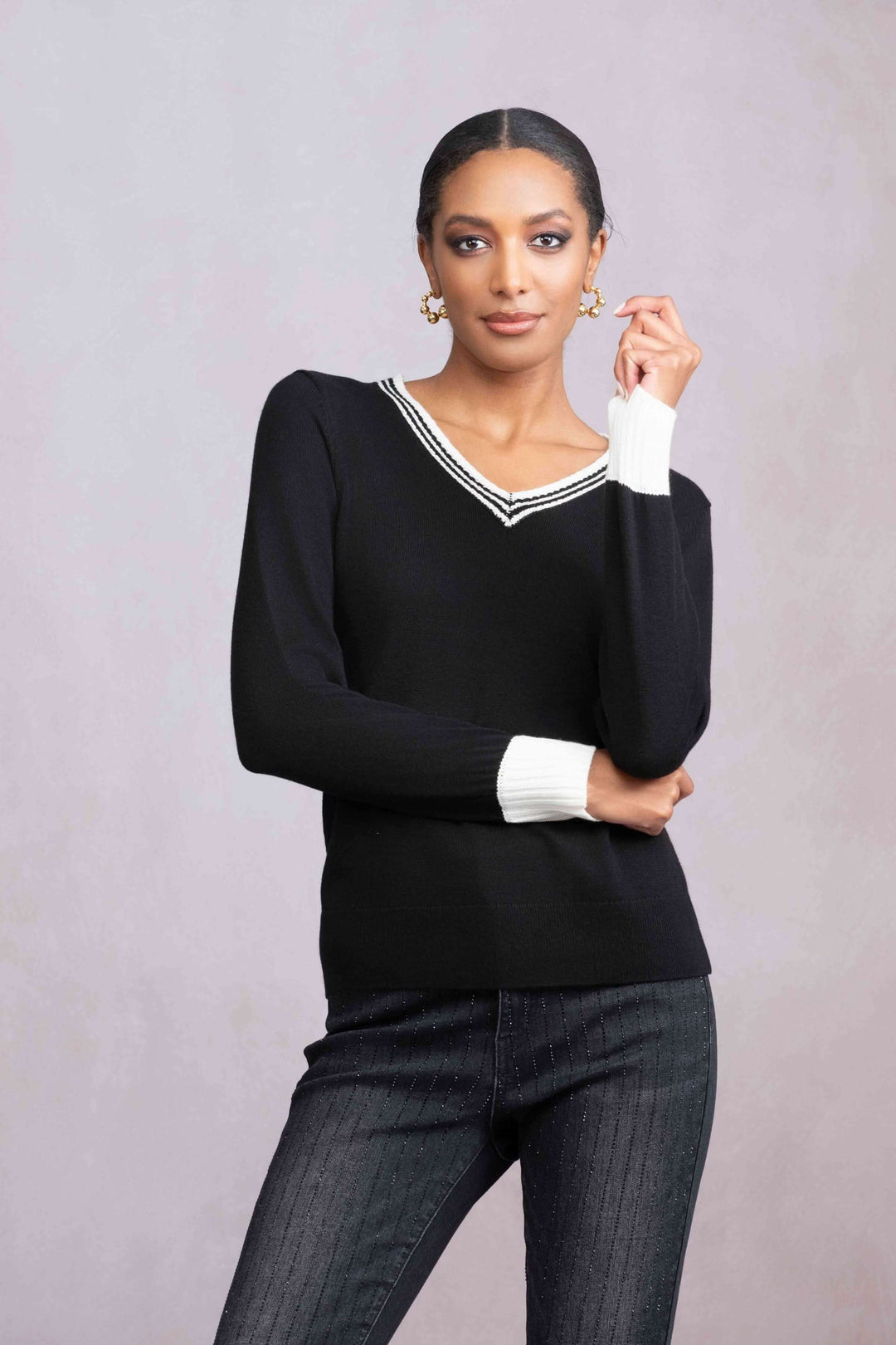 Chandail col V noir avec finitions contrastées, porté avec un jean, style moderne et élégant.