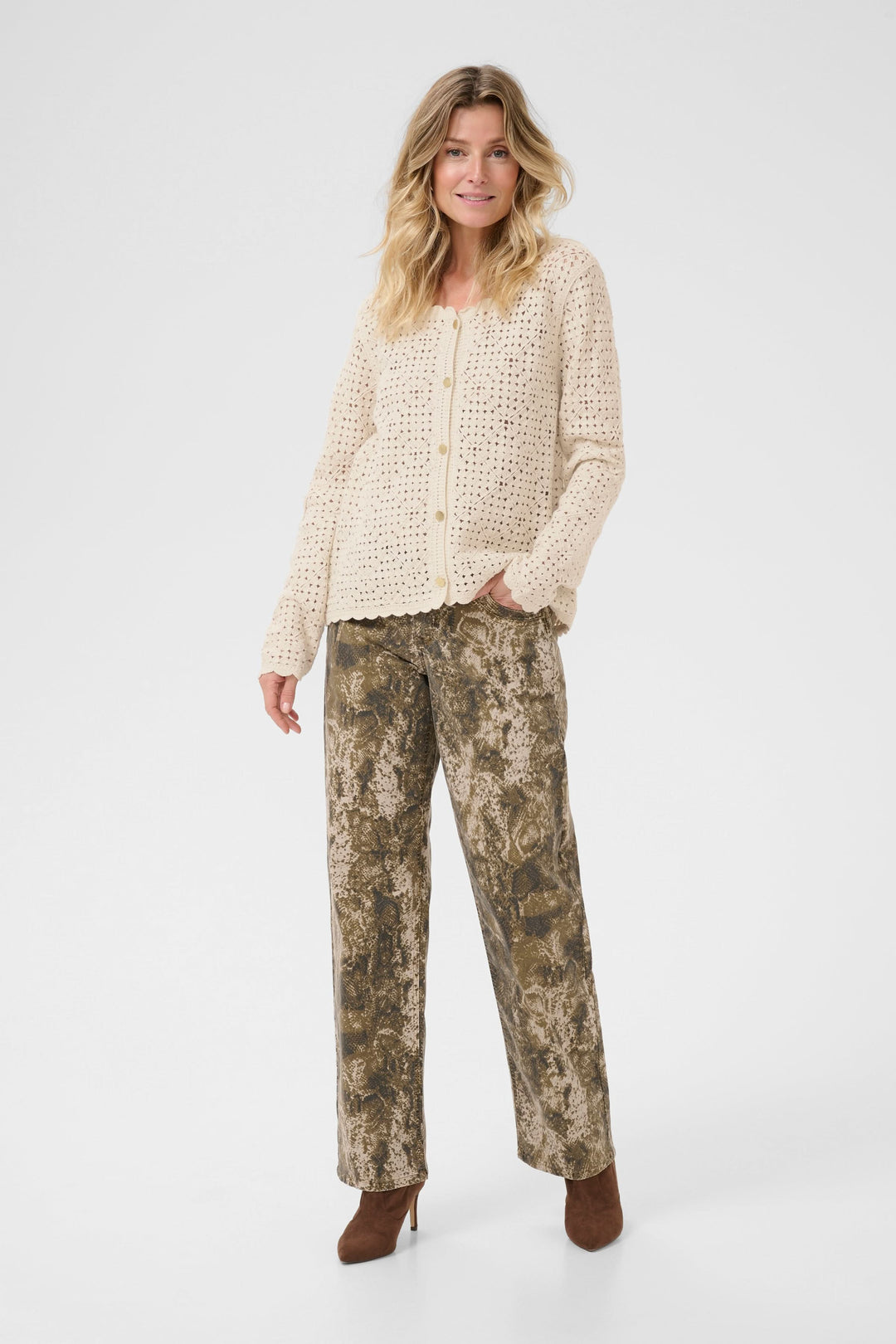 Femme portant un cardigan ajouré crème avec un pantalon imprimé, pour un look rétro et féminin.